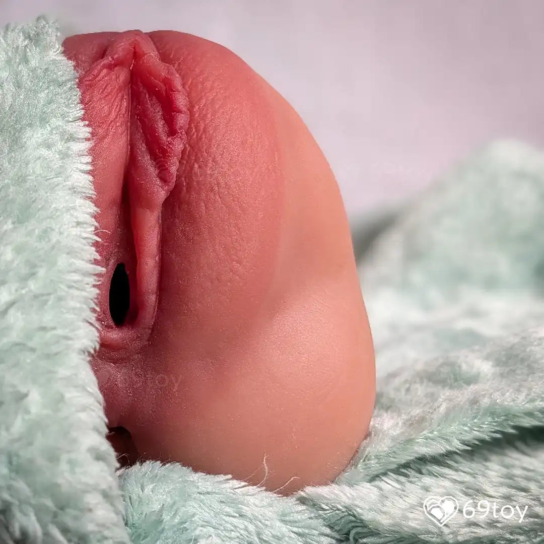 Close-up of a realistic silicone model of a female pussy organ wrapped in green fabric.